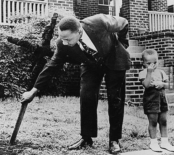 马丁·路德·金跟儿子在他们的前院把烧焦的十字架移除 - 1960