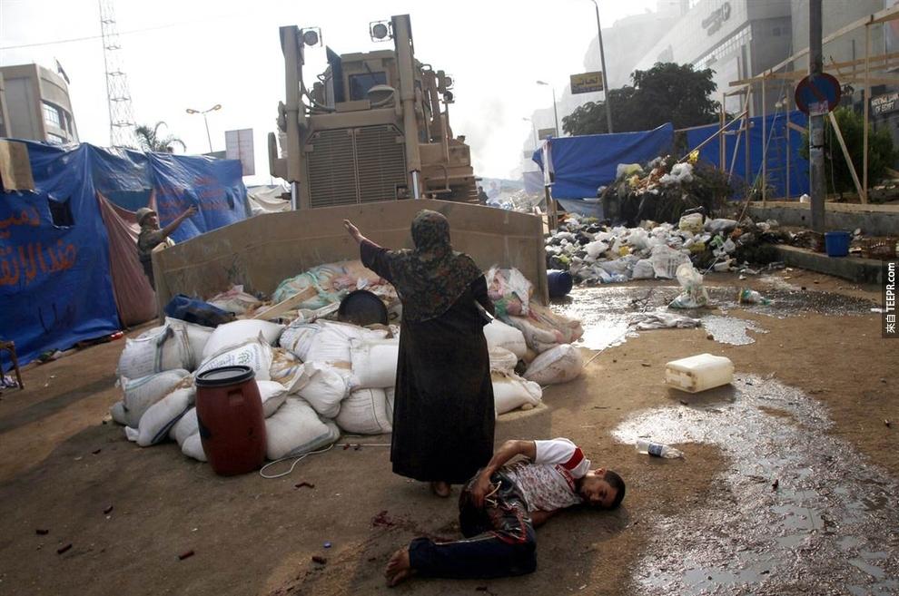  一名女子档在一台军用的推土机，保护着一名受伤的示威者 (埃及2013)