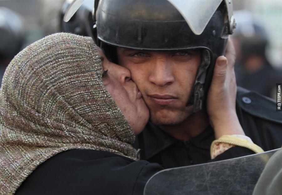 在埃及推翻穆巴拉克政府的时候一名埃及女士亲吻一名警察 (埃及 2011)。