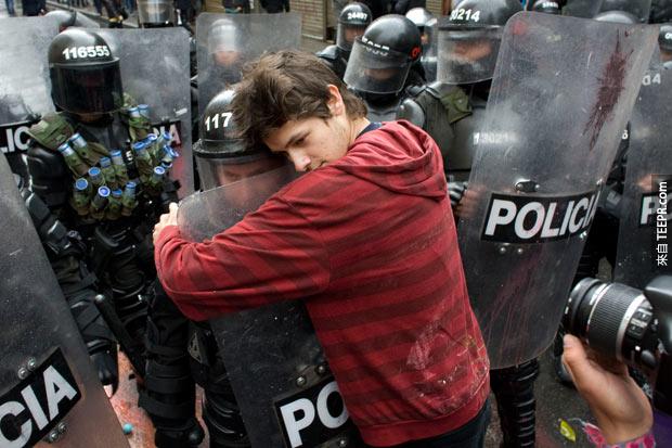 一个支持教育改革的示威者拥抱一名警察。(波哥大，哥伦比亚 2011)