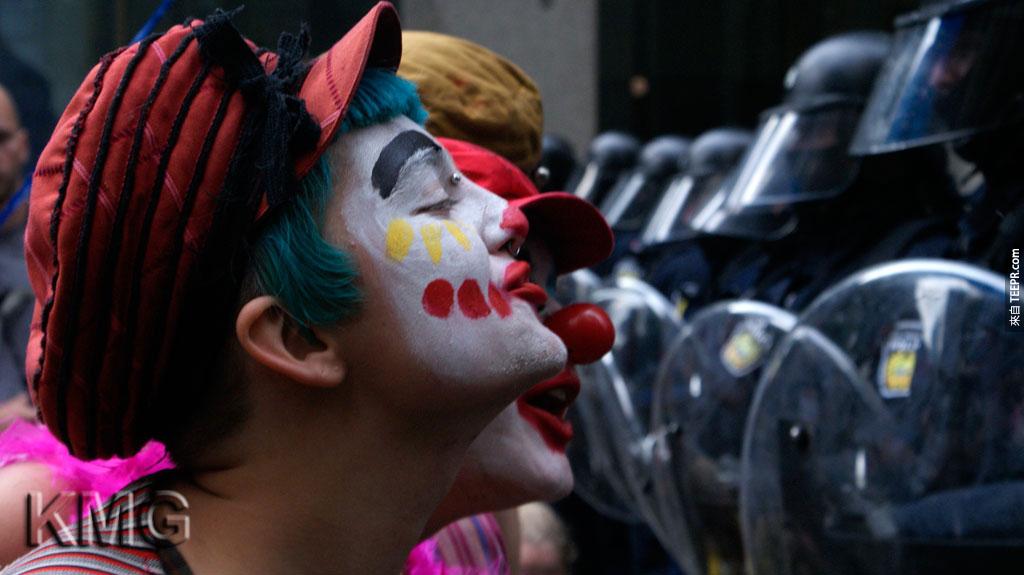 一些穿成小丑的示威民众提供娱乐服务给站守G20的侍卫 (多伦多，加拿大 2010)