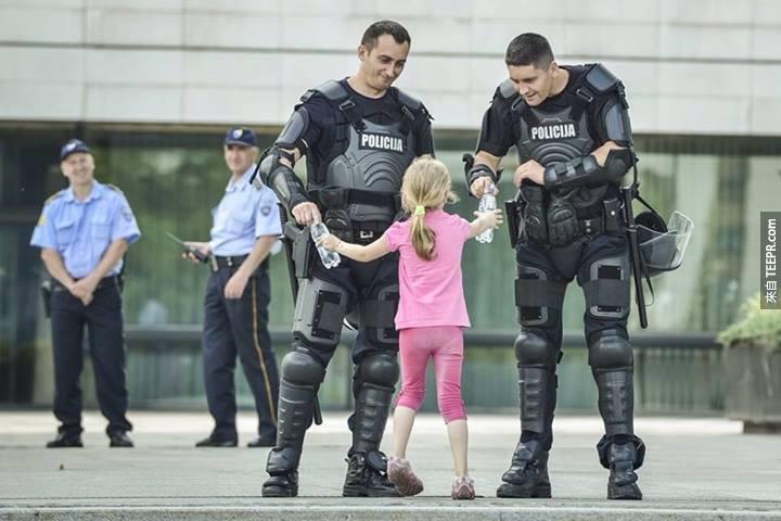小女孩提供水給兩名警員 (波斯尼亞 2013)。