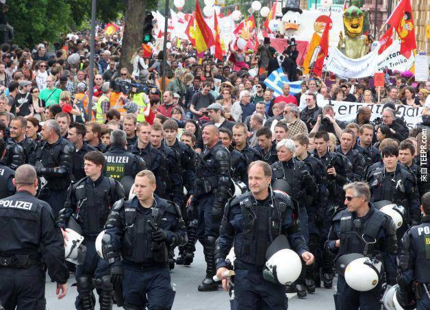 德国的防暴警察把他们的头盔摘下来护送示威者 (法兰克福，德国 2011)。