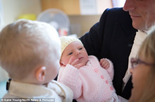 Gareth Hutchinson 抱着自己的女儿，在这么特殊的日子下诞生的她，将被命名为 Amanda 。