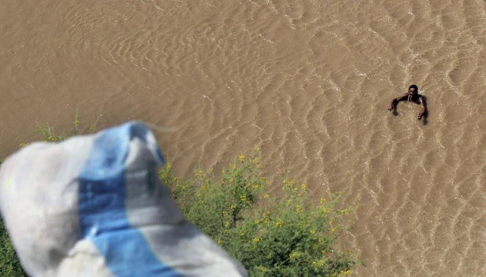 39. 在巴基斯坦木爾坦 (Multan) 的洪水中，一個男人正在等待直升機的救援包裹。在這場洪水當中，有上百人不幸死去。