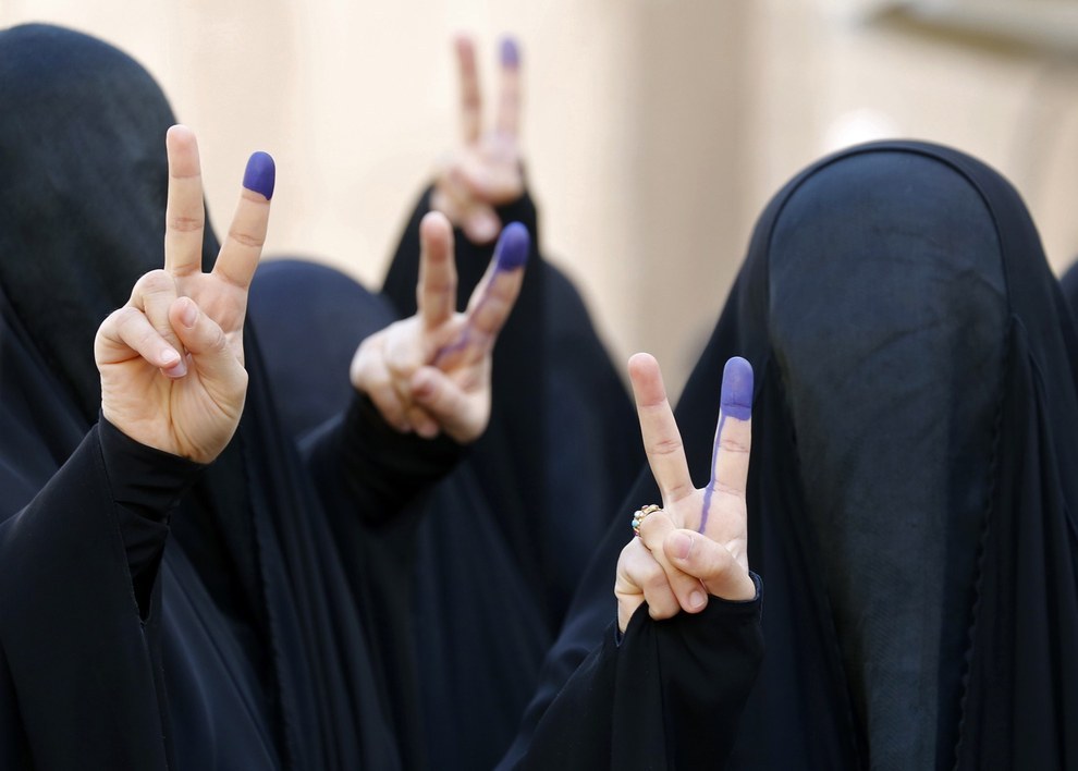 38. 在美軍撤退巴格達後，蒙面的伊拉克女子正展示著首次投票後的手指頭。