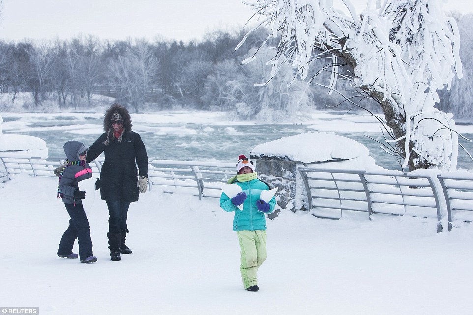 A family walks through the snow near the frozen Niagara Falls in Niagara Falls on Tuesday