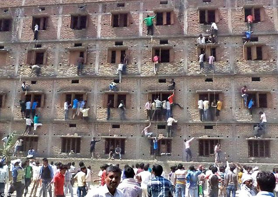 Relatives of those sitting exams inside a school scale the walls of the building in order to pass the students notes during their test