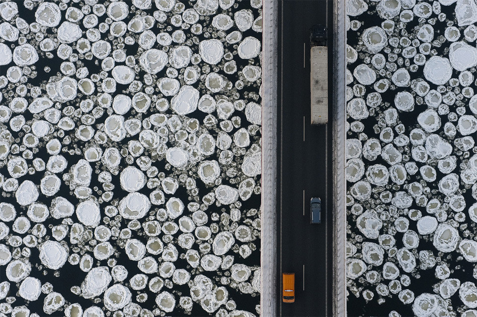  An aerial view of a bridge over icy, frozen water.