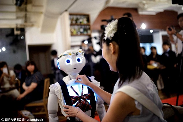 A woman wearing a pretty white hairband adjusts one of the 'helper' robot's shirts during the event
