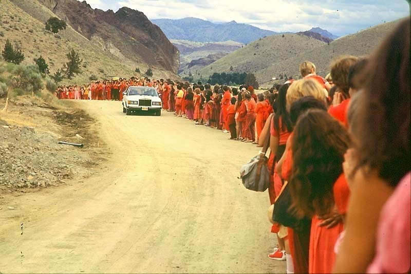 Spiritual Leader Bhagwan Shree Rajneesh (Osho)  driving a Rolls Royce through a crowd of followers in Oregon. He did a daily drive-by to greet his dedicated followers, who came from all over the world to see him.