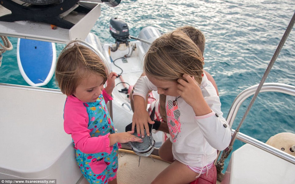 The curious young sailors get up close to the fish that stick to the bottom of their 41ft boat