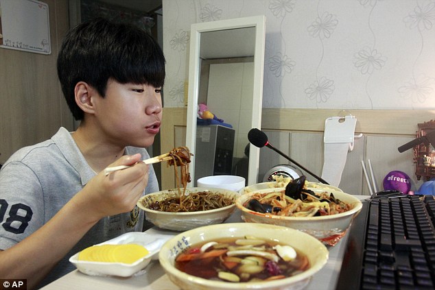 Hungry: South Korean teenager Kim Sung-jin, 14, gorges on fast food in front of his webcam every evening