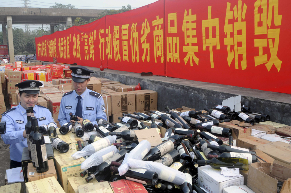 Police officers check bottles of confiscated fake wines before destroying them in Nanning