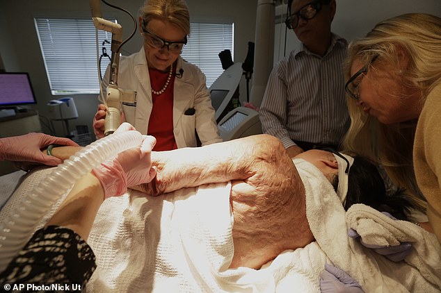 Dr. Jill Waibel, left, applies a laser to the arm of Kim Phuc to reduce the pain and appearance of her burn scars in Miami. Phuc's husband, Toan Huy Bui, stands at center with patient care coordinator, Deborah Lomax, right. While she spent years doing painful exercises to preserve her range of motion, her left arm still doesn't extend as far as her right arm.