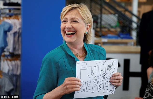 U.S. Democratic presidential nominee Hillary Clinton laughs while holding a design that was given to her by a child while visiting Raygun, a clothing store, in Des Moines, Iowa August 10, 2016. REUTERS/Chris Keane