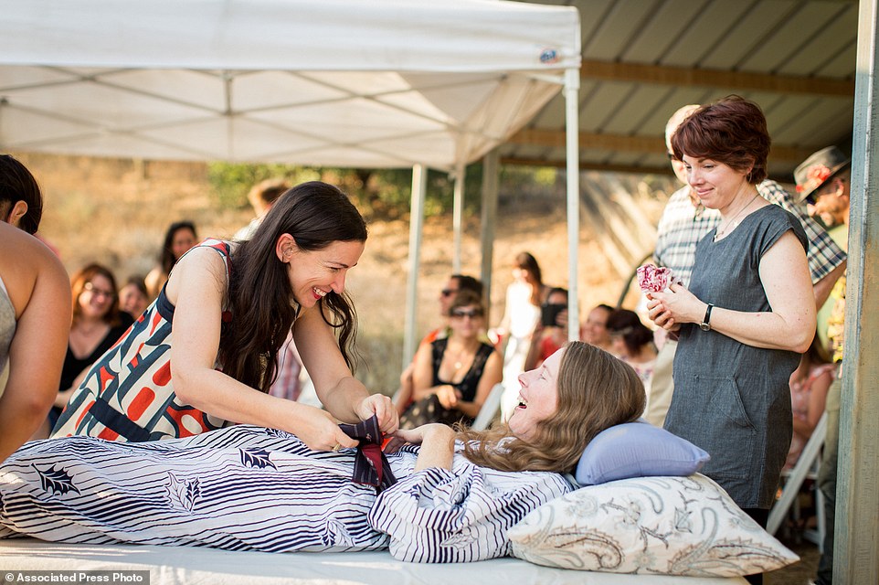 Amanda Friedland, left, adjusts her friend Betsy Davis's sash as she lays on a bed during her 'Right To Die Party' in Ojai, surrounded by friends and family