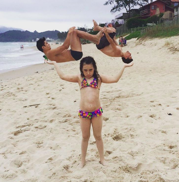This picture of a little girl holding up two flipping Brazilian gymnasts: