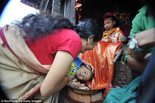 A Mother helps her child to take a blessing from the Living Goddess of Patan, who is called Yunika