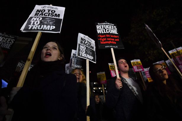 Demonstrators hold placards that read "No to racism, no to Trump" during a protest outside the US Embassy in London