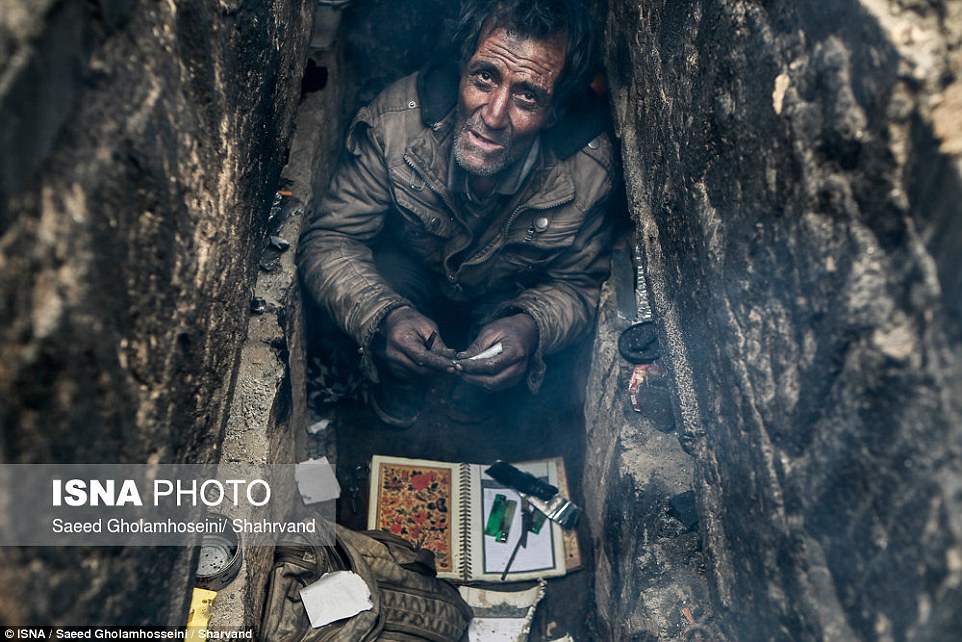 A man looks up from a grave in which he is taking shelter 12 miles from Iranian capital Tehran, in pictures which have shocked the country