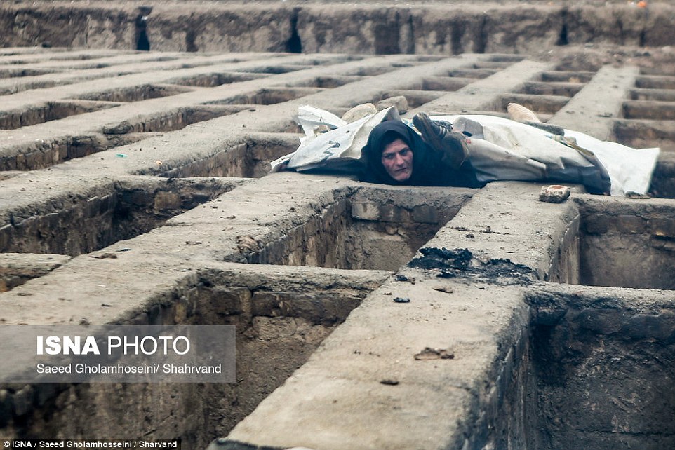 A woman emerges from a grave, in a cemetery where around 50 homeless men, women and children are living, according to reports in Iran