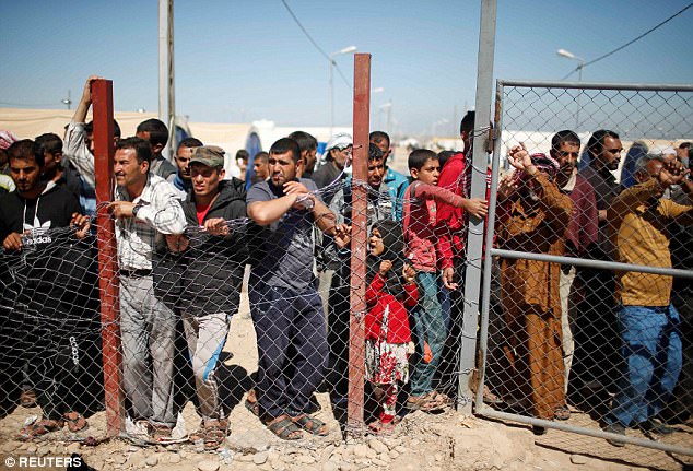 Displaced Iraqis who had fled their homes pictured waiting for food supplies at Hammam al-Alil camp 