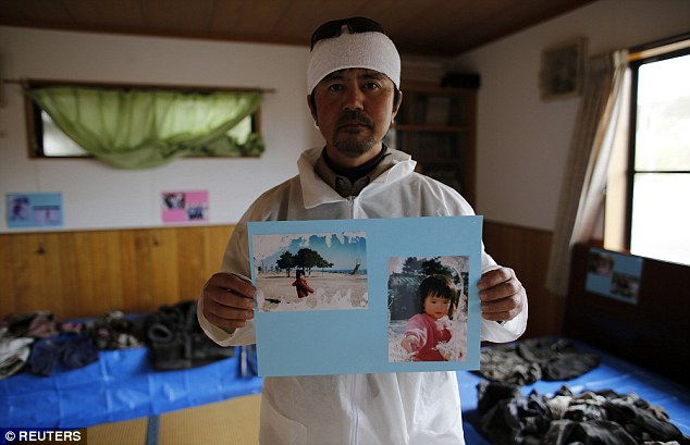 Mr Kimura holds up photos of his seven-year-old daughter who was swept away by the wall of water