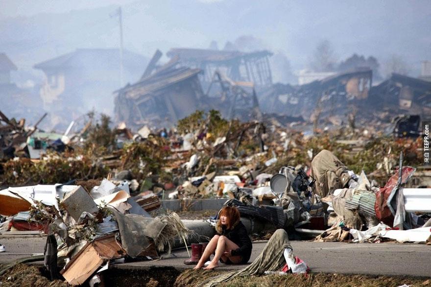 一名女子心神無主的坐在311地震海嘯所留下來的廢墟裡 - 2011年3月