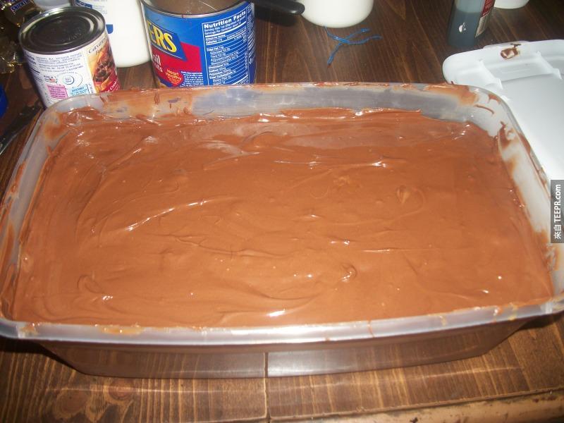 太好了，我們快做完了。現在在在最上面鋪上一層剛剛做的巧克力奶油花生醬把這一整個巨大蛋糕罩住。這樣我們7公斤的1兆卡路里的巨大花生巧克力就完成了。現在就要等它冷卻。
