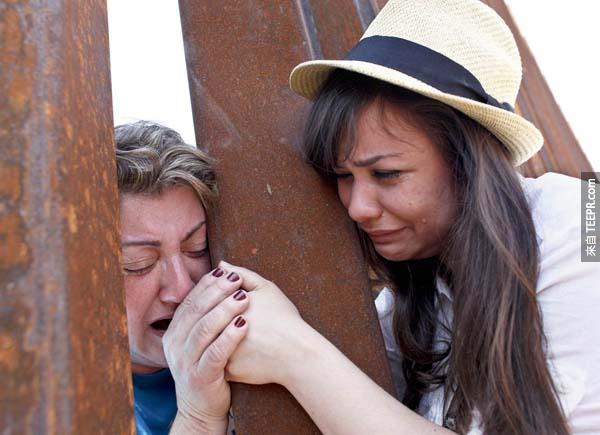 在亞利桑那州的邊境柵欄，一位女孩緊抓著她六年前被驅逐至墨西哥的母親的手。
