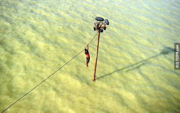 一位在印度的年轻男孩试图逃避洪水而被迫悬吊在电缆线上。