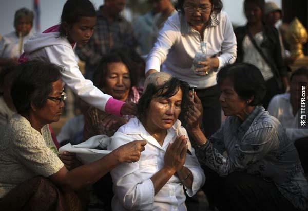 这位女士在柬埔寨国王葬礼之前，正在进行剃发以象征哀悼的情绪。