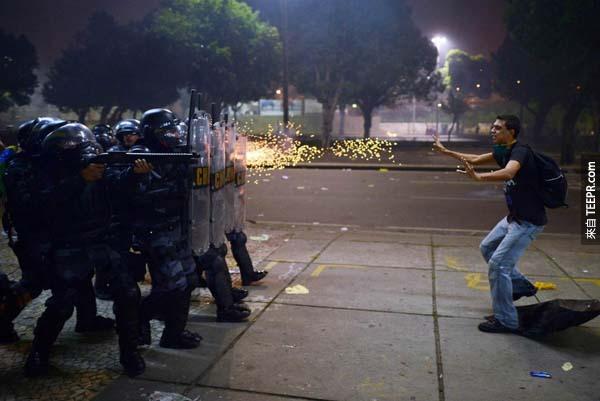 在巴西里约热内卢（Rio de Janiero）爆发抗议冲突后， 一名示威游行者被警察用橡皮子弹攻击。