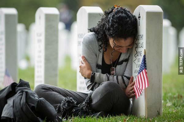阿灵顿国家公墓一角，这位寡妇悲伤着紧靠在阿富汗战争而死去的丈夫墓碑前。
