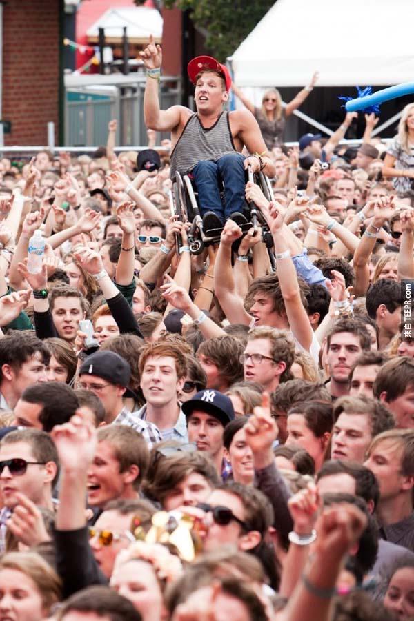 25.) 群众将一位坐轮椅的年轻小伙子，抬起来欢呼。