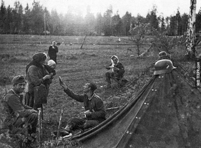 16.) 一名德國軍人將他的食物分給當地的俄羅斯媽媽。