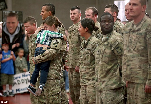Heart-warming: Kathryn Waldvogel, 25, dropped her military stance to cuddle three-year-old Connor after returning to Chisholm, Minnesota, from a nine-month tour with the National Guard in Afghanistan on Tuesday
