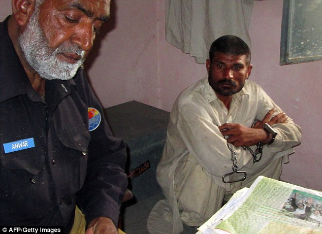 Pakistani villager Mohammad Arif Ali is seen next to an officer at a police station in Bhakkar district in April, 2014, after the head of a three-year-old boy was found at his home -- three years after he and his brother were jailed for the same offence