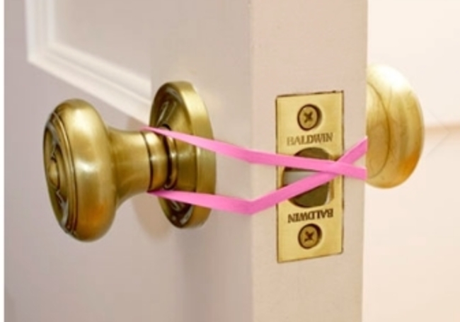 只要像圖片中這樣簡單的把橡皮圈繞在門把上，就可以避免小朋友不小心把自己鎖在廁所或房間裡了！