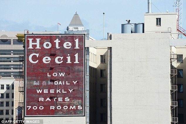 A worker stands on a water tank on the roof of the Hotel Cecil where the 21-year-old was found