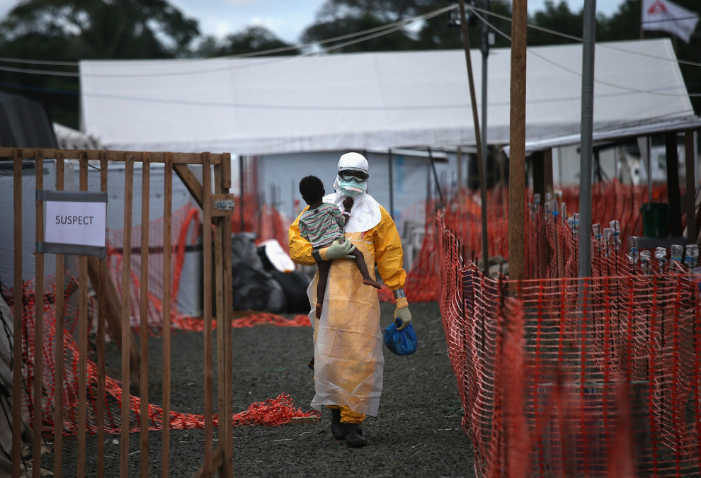 43. 在利比里亚 (Liberia) 一位无国界医生穿着防护装备、抱着一位疑似患有伊波拉病毒的孩子。