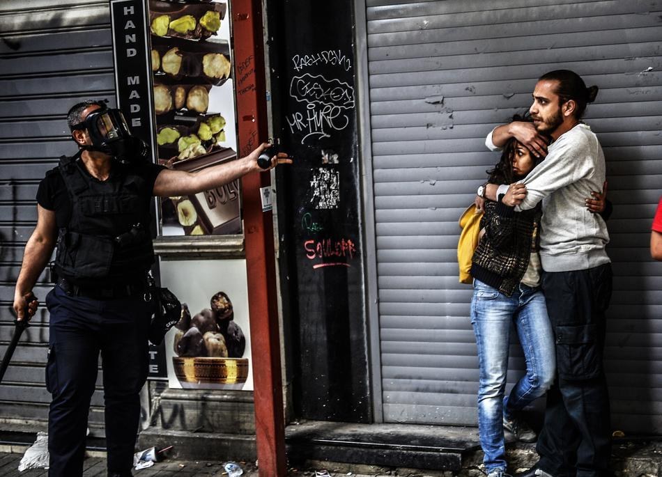 17. 在2013年土耳其反政府抗议运动满周年时，在碰上警察的时候，一位男性抗争者正在保护另一名女性抗争者。