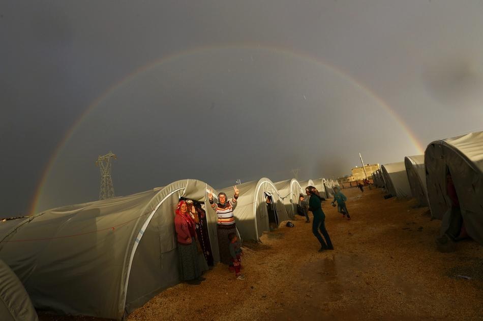 45. 從敘利亞艾因阿拉伯 (Kobani) 逃出的庫爾德難民比出勝利手勢，外頭還有一道彩虹。