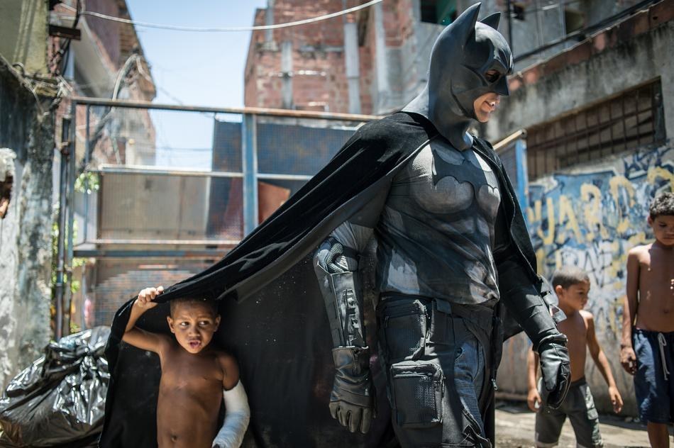 44. 在巴西世足赛场地附近，孩子正在跟扮演蝙蝠侠的人玩耍。
