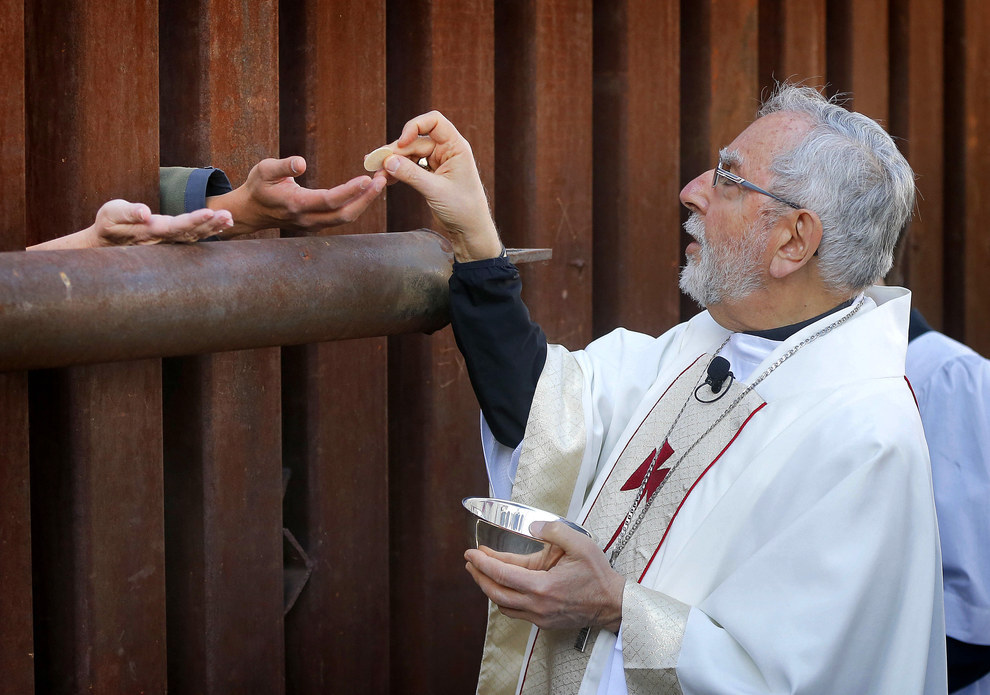 26. 在墨西哥交界处，图森教区主教Gerald F. Kicanas与另一栅栏侧的墨西哥居民交流。