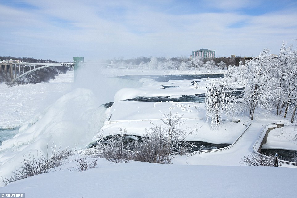 A snow-covered landscape is seen around the frozen Niagara Falls