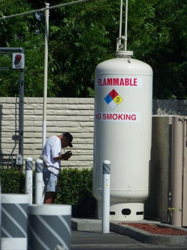 在易燃化學氣瓶旁抽煙的男子...
