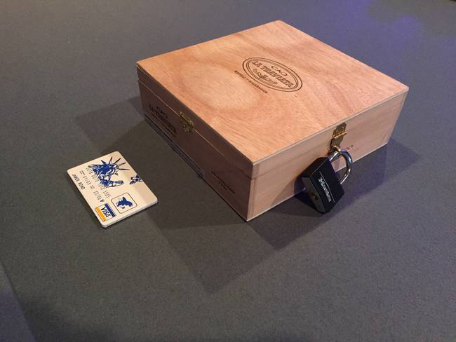 The groomsman says, "Here's what I was handed. At first I thought it was just cigar box with some cigars from Costa Rica and he locked them so TSA wouldn't get into the box as easily." A closer look would make him see that this wasn't the case.