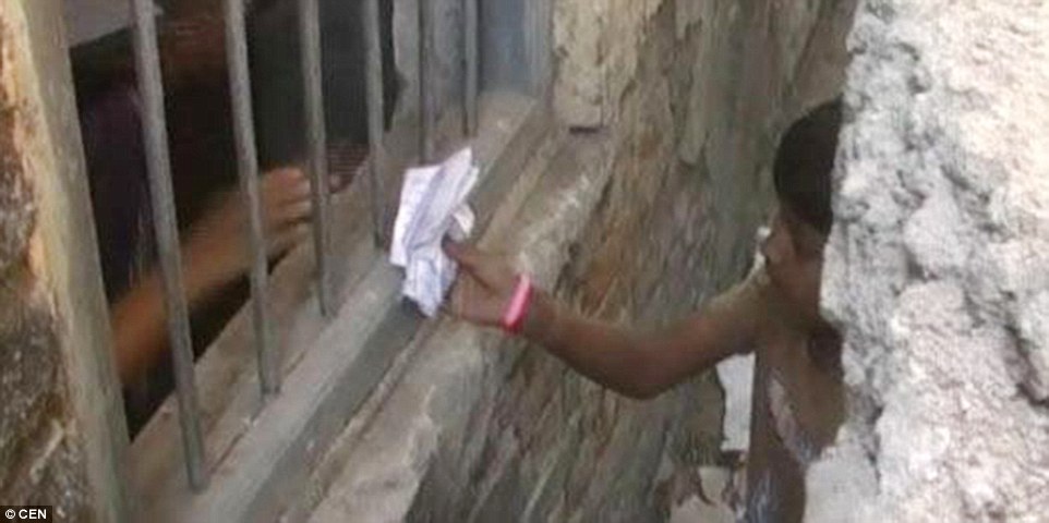 Many in India were left shocked after seeing the brazen cheating methods. Here a person is pictured handing a relative notes through a window